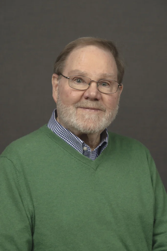 Man in a green blazer, studio headshot on dark background, Portland