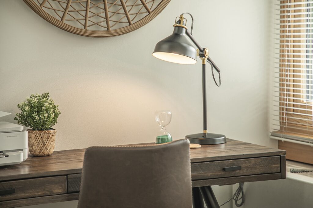 Close-up of a wooden desk with a vintage-style lamp, small plant, and cozy home office vibes