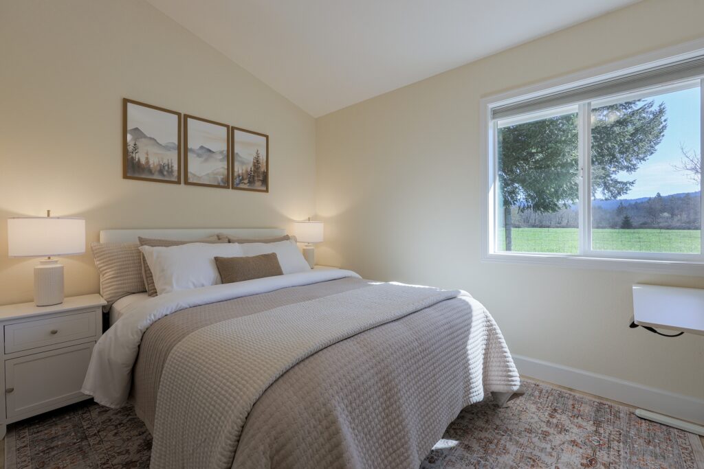 Bright bedroom interior with neutral tones, comfortable bedding, and a view of a red bridge through the window