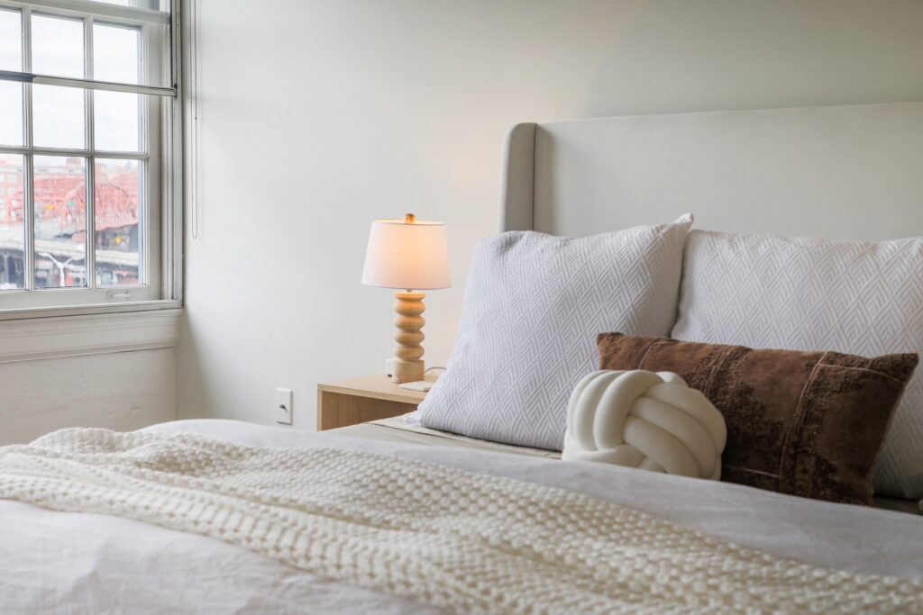 Minimalist bedroom with a large window overlooking a city view.