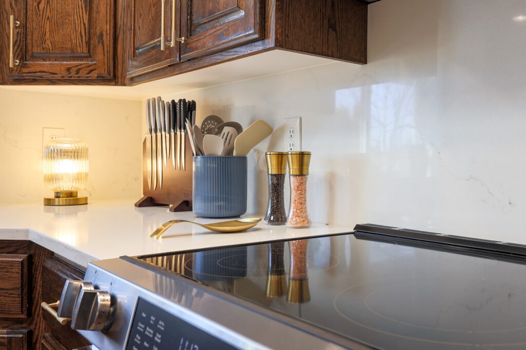 Close-up of a modern kitchen counter with gold accents, wooden cabinets, and professional staging