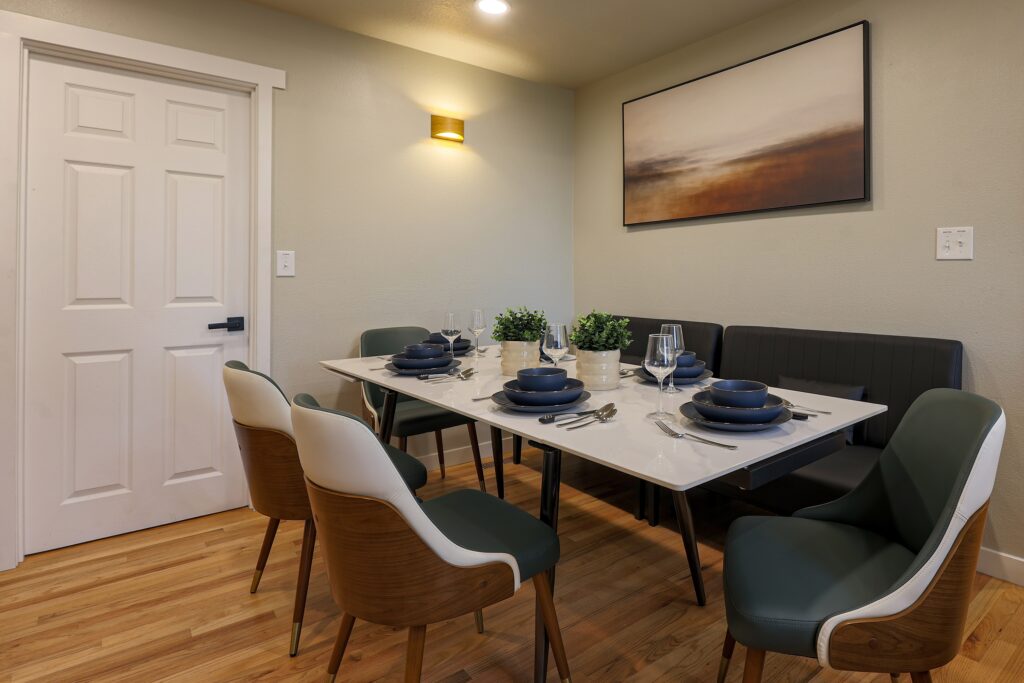 Modern dining room setup with a white marble table, elegant chairs, and professional table setting for a dinner party.